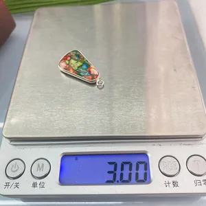 Vue macro d'un pendentif en pierre mosaïque multicolore pesant 3g sur une balance