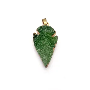 Détail d'un pendentif en druzy de cristal vert en forme de feuille avec bords dorés