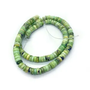 Dettaglio di perle cilindriche in pietra naturale verde chiaro con venature per gioielli DIY