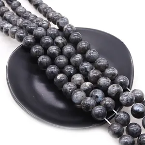 Polished natural labradorite beads with blue flash luster on a dark tray accessory