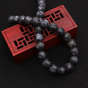 Natural black labradorite round beads showing blue iridescent flash on a wooden display