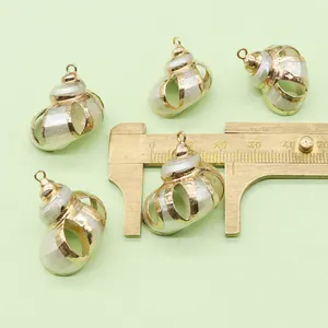 Macro view of five white shell conch pendants with gold hollow frames and measuring caliper