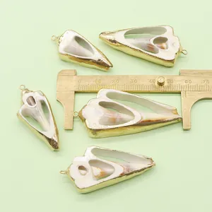 Macro detail of natural shell pendants with gold edges and brass caliper measurement