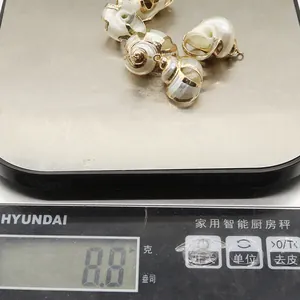 Detailed view of natural shell pendants with gold trim on a digital scale weighing 8.8g