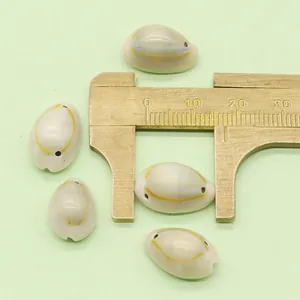 Macro detail of natural cowrie shell beads measured with brass calipers for DIY jewelry