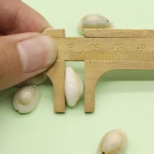 Detail of 10mm natural shell pendant being measured with a brass caliper for DIY jewelry