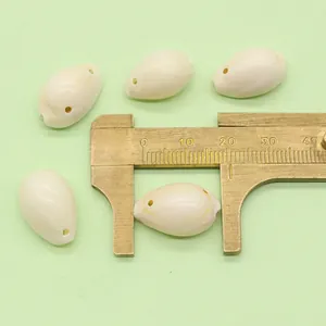 Macro shot of cream shell pendants with two pre-drilled holes measuring 22mm on calipers
