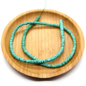 Macro view of turquoise heishi beads on a wooden tray for DIY jewelry making