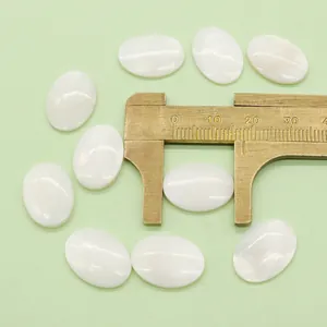 Macro shot showing measurement of a white oval mother of pearl shell bead using a caliper