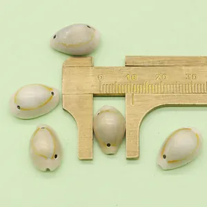 Macro shot of natural shell beads with pre-drilled holes being measured by a brass caliper