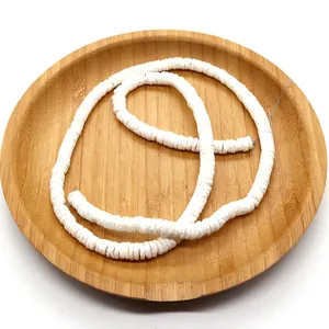 Close-up of white Heishi clay beads arranged in a wooden tray for DIY jewelry making