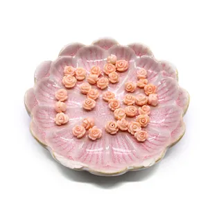 Macro shot of pink synthetic coral rose beads for DIY jewelry in a seashell dish