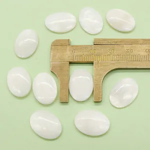 Macro shot of oval white mother of pearl cabochons measured with a brass caliper