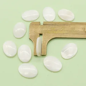 Macro shot of oval white mother of pearl cabochons showing 4mm thickness with caliper