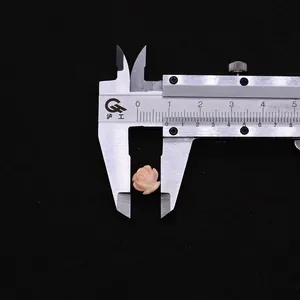 Macro view of 10mm pink synthetic coral rose bead being measured with a caliper