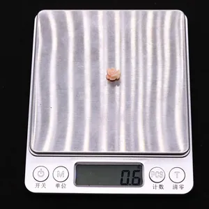 Macro shot of pink coral rose bead weighing 0.6 grams on a digital scale for DIY jewelry