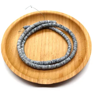 Macro shot of natural gray-white shell disc beads for DIY jewelry making in wooden tray
