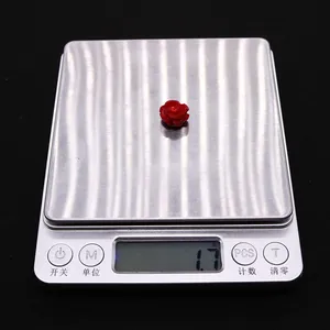 Makrofoto einer roten Rosen-Korallenperle auf einer Digitalwaage mit 1,7g Gewicht