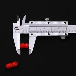 Κοντινή λήψη κόκκινης σκαλιστής χάντρας 12mm που μετριέται με ψηφιακό παχύμετρο