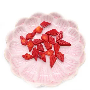 Red synthetic coral leaf charms for DIY necklaces with detailed vein texture in a tray