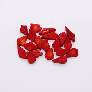 Detailed view of red leaf-shaped synthetic coral beads with engraved vein textures for DIY