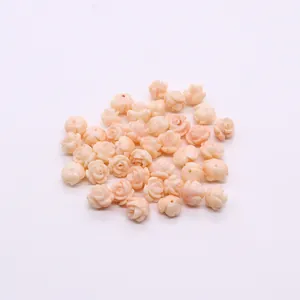 Macro shot of light pink synthetic coral rose beads with detailed floral carvings for DIY