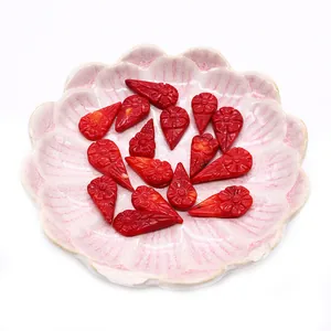 Red synthetic coral drop-shaped flower charms for DIY jewelry making in a pink dish