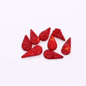 Detailed view of red carved synthetic coral teardrop beads with daisy floral patterns