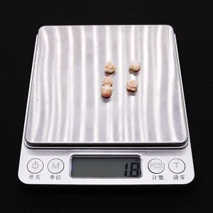 Detail shot of five carved pink coral rose beads on a digital scale weighing 1.8 grams