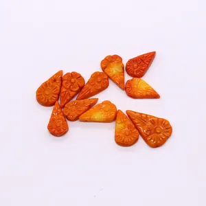 Detailed macro view of eleven orange carved coral teardrop beads with flower patterns