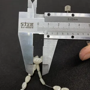 Measuring white shell leaf bead length of 10mm with caliper on black background