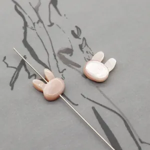 Macro shot of pink rabbit-shaped natural shell beads showing horizontal hole detail