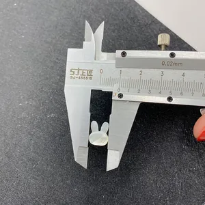 Macro shot measuring a white rabbit shell bead using calipers showing a width of 10mm