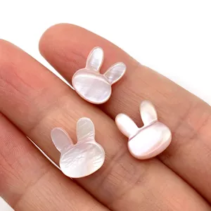 Pink mother of pearl rabbit beads for DIY jewelry making shown on a fingertip
