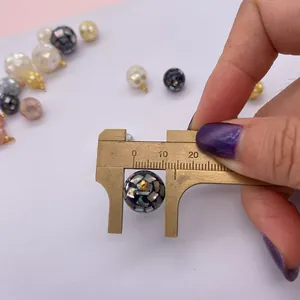 Macro shot of a 10mm mosaic shell bead pendant measured with a digital caliper