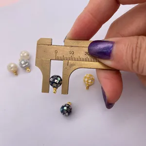Macro view of 10mm round mosaic shell pendant being measured with a caliper