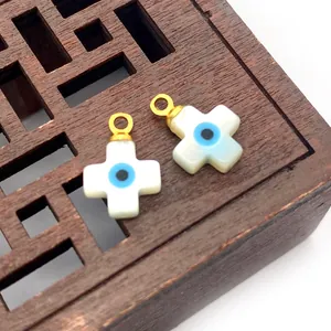 Macro detail of natural shell cross pendants with blue evil eye on a wooden tray