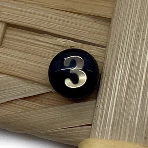 Macro shot of circular black shell bead with gold number three for DIY jewelry