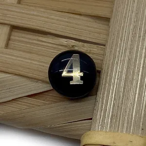 Macro shot of a black round shell bead featuring a metallic silver number 4 for DIY jewelry