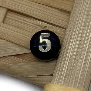 Macro view of polished black shell bead featuring silver number 5 for DIY jewelry