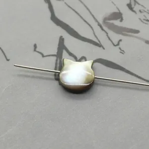 Macro shot of owl-shaped natural shell bead with iridescent luster and center drill hole