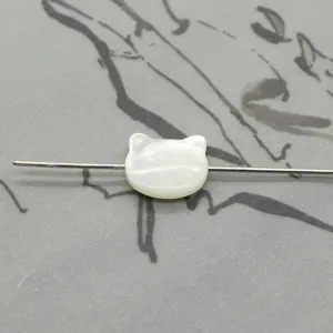 Macro view of cat-shaped white mother of pearl bead showing natural iridescent texture