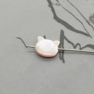 Macro detail of natural pink shell owl-shaped bead with iridescent luster for DIY jewelry