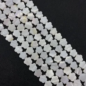 Macroshot van witte schelpkraaltjes in bloemvorm met iriserende glans voor DIY sieraden