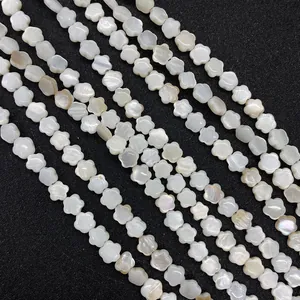 Primer plano de cuentas de nácar blanco con forma de flor sobre cuero negro rugoso