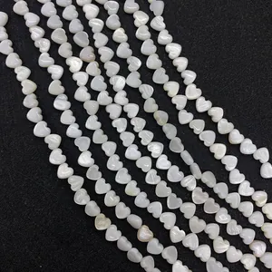 Detalle macro de cuentas de nácar blanco en forma de corazón con brillo iridiscente