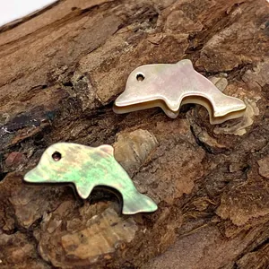 Delfinförmige Naturmuschel Anhänger mit goldener Metallbasis auf Baumrinde