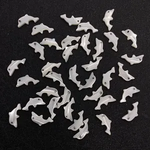 Delfinförmige Perlen aus Natürmuschel für DIY-Schmuckherstellung auf schwarzem Grund
