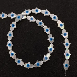 Macro detail of natural mother of pearl Hamsa beads with blue evil eye pattern