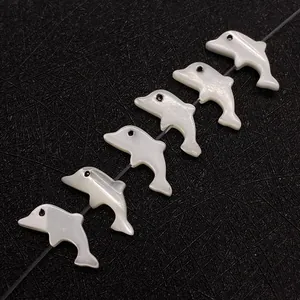 Makro-Detail von sechs delfinförmigen Perlmuttperlen mit irisierendem Glanz auf schwarzem Band